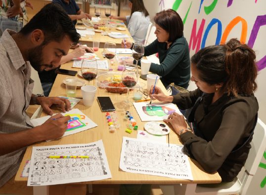 Taller de pintura para adultos en la mesa larga del salón WeGlow en la Roma